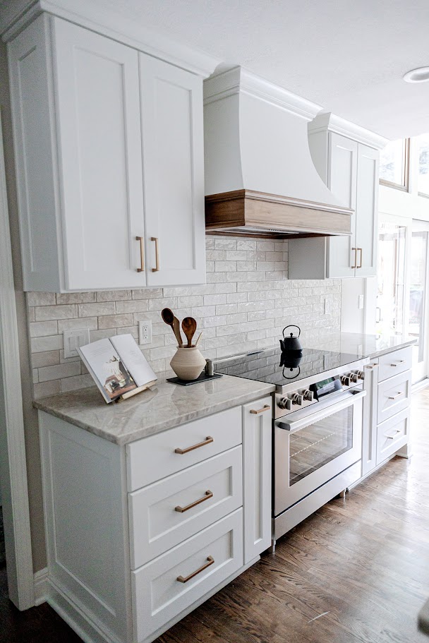 Remodeled kitchen with white shaker cabinetry, stone tile backsplash, gold hardware, and a stainless steel range in a Topeka home