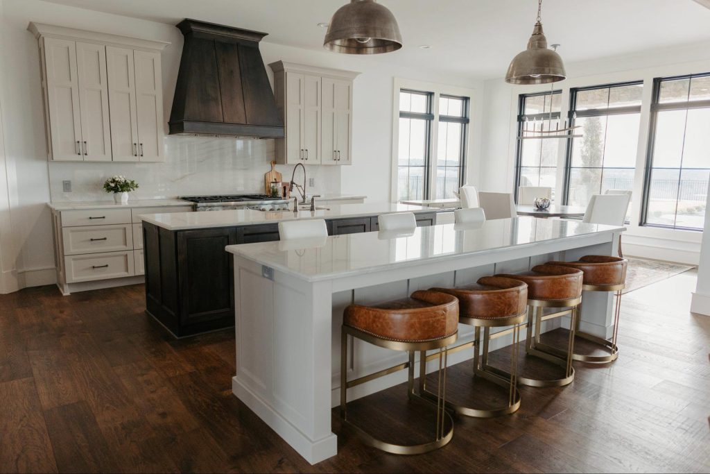 Custom kitchen remodel with large island, white cabinetry, and dark wood range hood in a Topeka home
