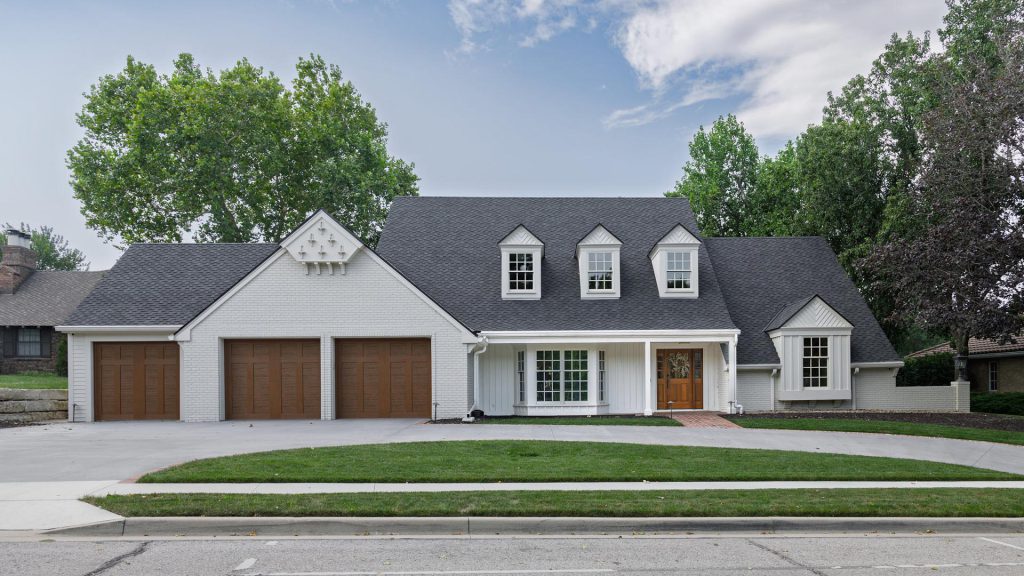 Front exterior of a whole-home remodel in Lawrence, Kansas, with dormer windows and a covered porch