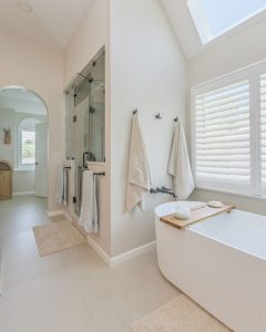 Spa-like primary bathroom with a freestanding tub, glass walk-in shower, and skylight in a Winston Brown remodel