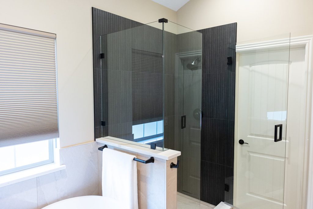 Dark tile walk-in shower next to a freestanding tub in a spa-like bathroom remodel