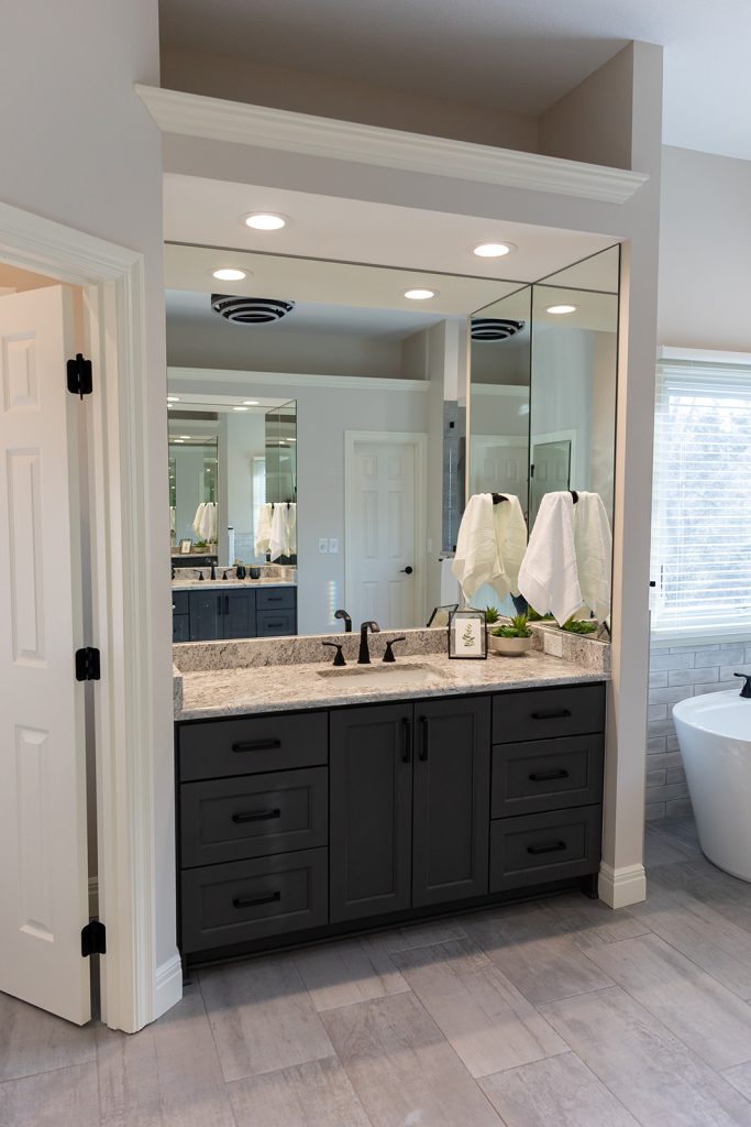 Dark wood vanity with an arched mirror and a freestanding tub visible nearby