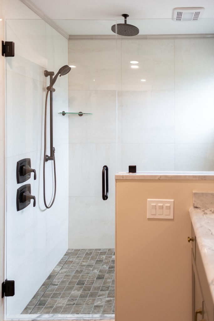 Walk-in shower with oil-rubbed bronze fixtures and a mosaic tile floor