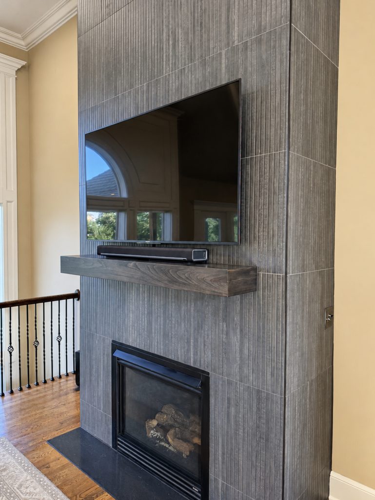 Close-up of the Elan Ribbon Black tile and alder mantel on a remodeled fireplace